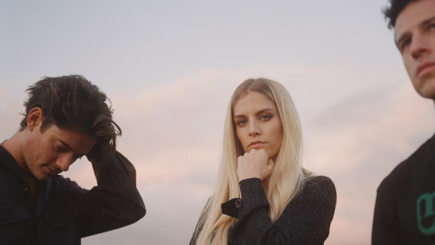 London Grammar dressed in black, with sunset lit sky behind them