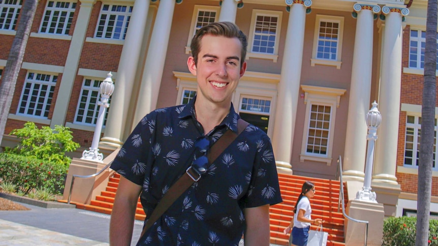 Alec stands outside a university building at QUT Gardens Point