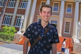 Alec stands outside a university building at QUT Gardens Point