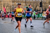 A woman runs in the London Marathon under Big Ben.