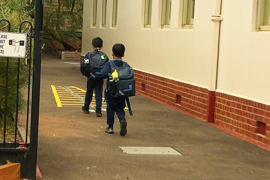 two young boys walking to school carrying back packs