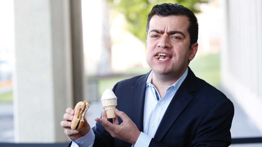 New South Wales Senator Sam Dastyari pulls a stunt at Parliament House, with a mouthful of cheeseburger and holding ice cream