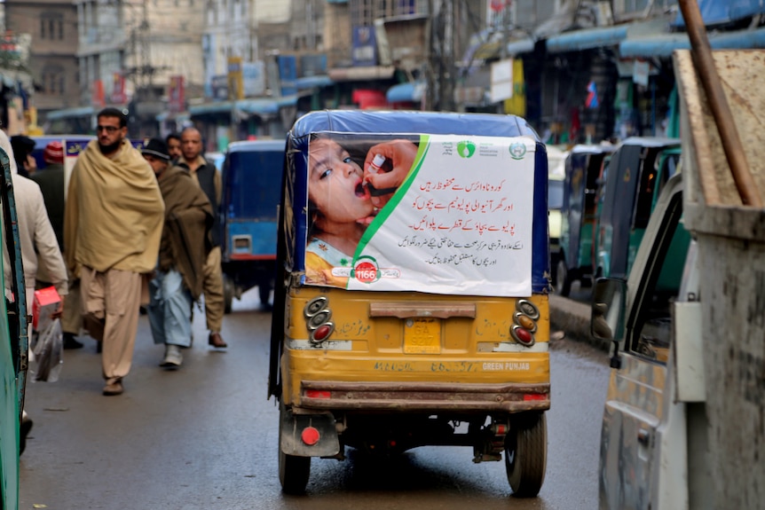  An auto rickshaw with a poster advertising an oral polio campaign, drives through a market in Peshawar, Pakistan.