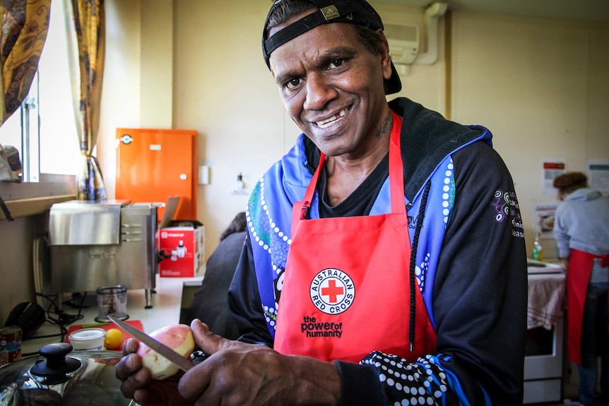 A man in the kitchen peels a potato