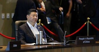 Xi Jinping sitting at the conference table at APEC.