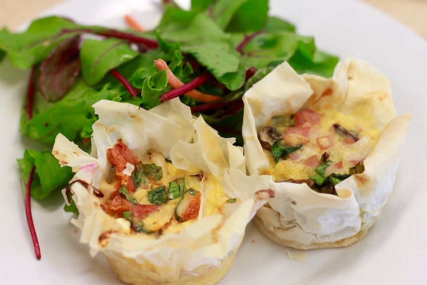 Close-up of minis quiches served with lettuce on a white plate