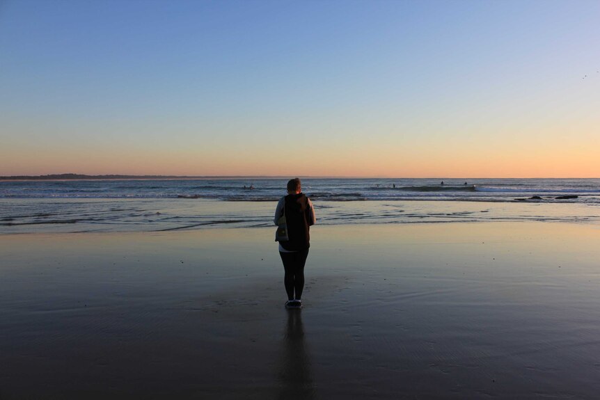 Ruth standing central in the photograph as the sun rises over Town Beach in Port Macquarie on a cold morning.