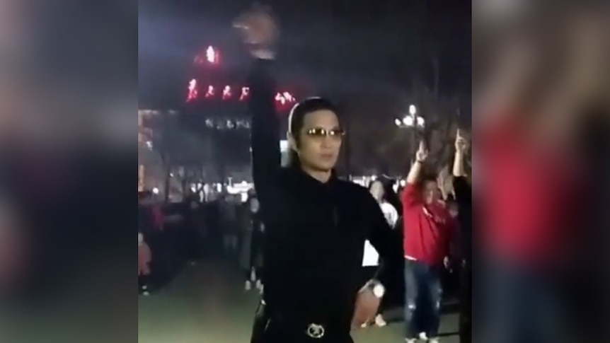 A dancing Chinese man wearing black and glasses.
