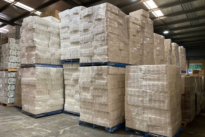 Photo of toilet paper stacked in a warehouse.