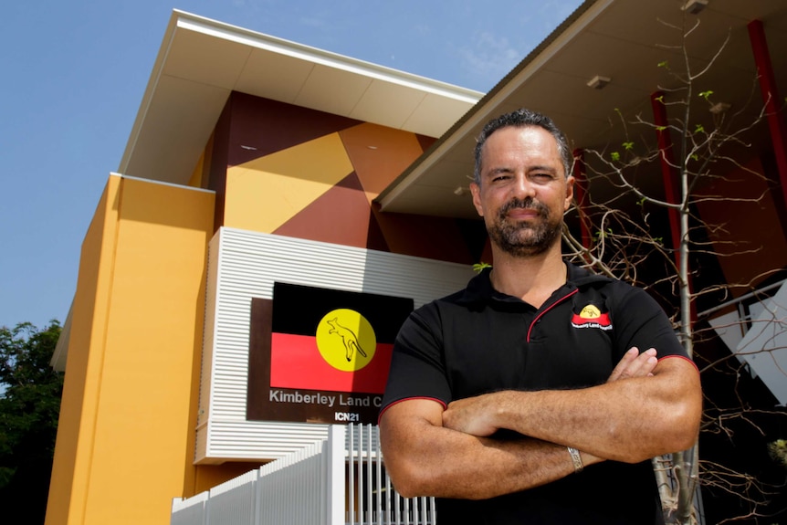 A man stands with arms crossed in front of the Kimberley Land Council building.