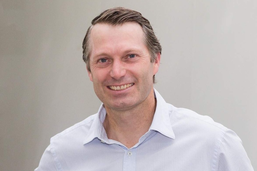 Rowan McMonnies, MD of Australian Eggs stands behind a conveyor belt with dozens of eggs.