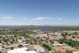 drone shot of houses with body of water and red ranges in distance