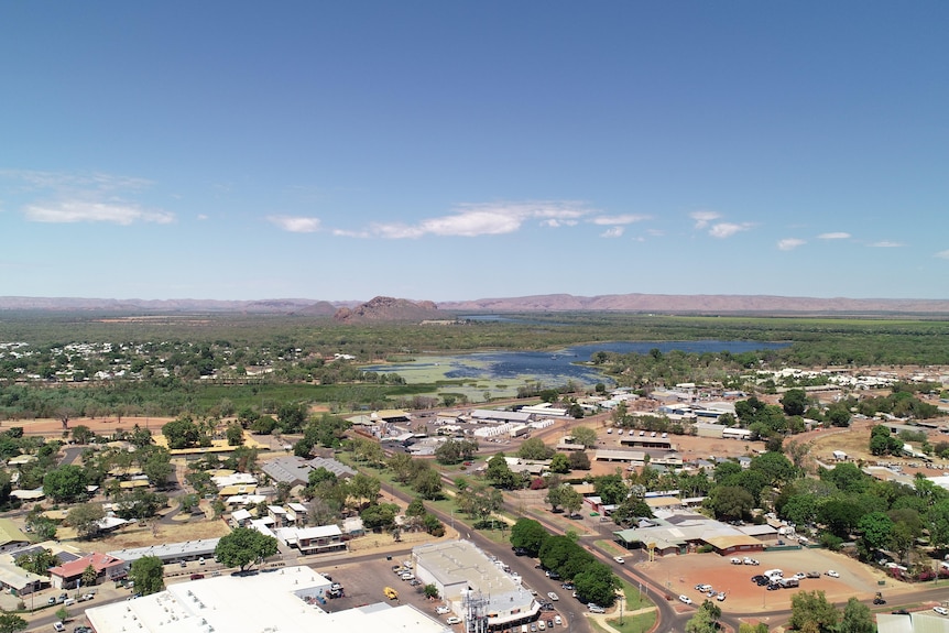 drone shot of houses with body of water and red ranges in distance