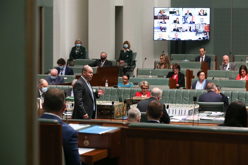 Josh Frydenberg speaks in the House of Representatives with faces on a screen watching on