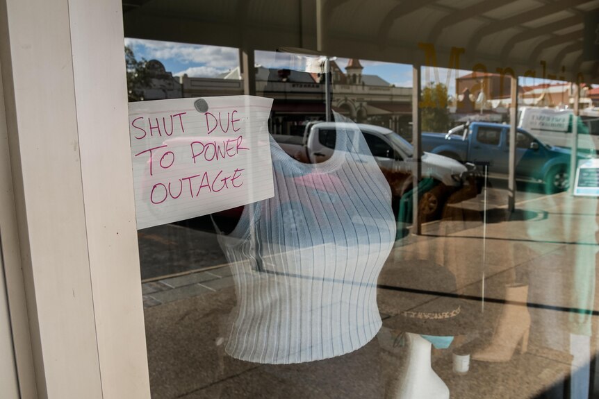 A sign posted in a shopfront saying it has shut due to a power outage.  