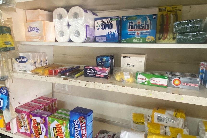 grocery items on a shelf like biscuits and washing detergent. 