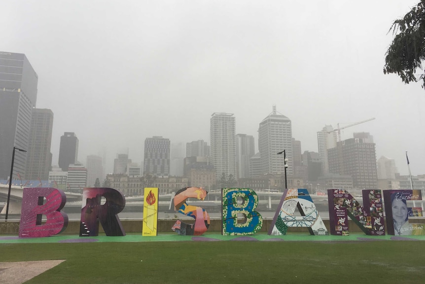 Heavy rain falls, the brisbane sign in the foreground and the city in the background