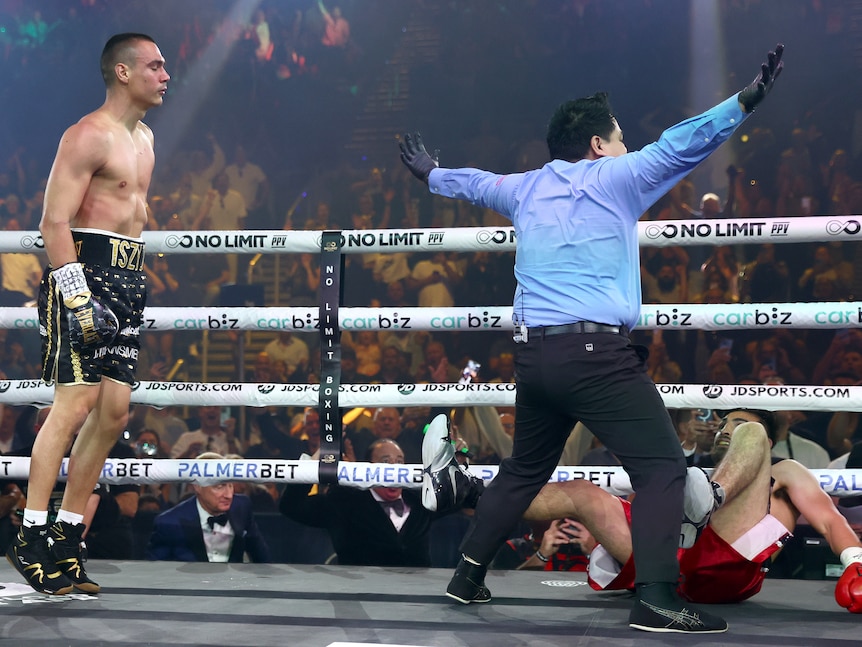 Boxer Carlos Ocampo lies on the canvas after being knocked out by Tim Tszyu, as a referee waves his arms to stop the fight.
