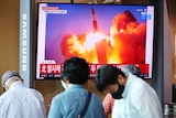 People watch a TV broadcasting of what appeared to be a pair of ballistic missiles firing