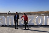 Two people in front of an amazon sign