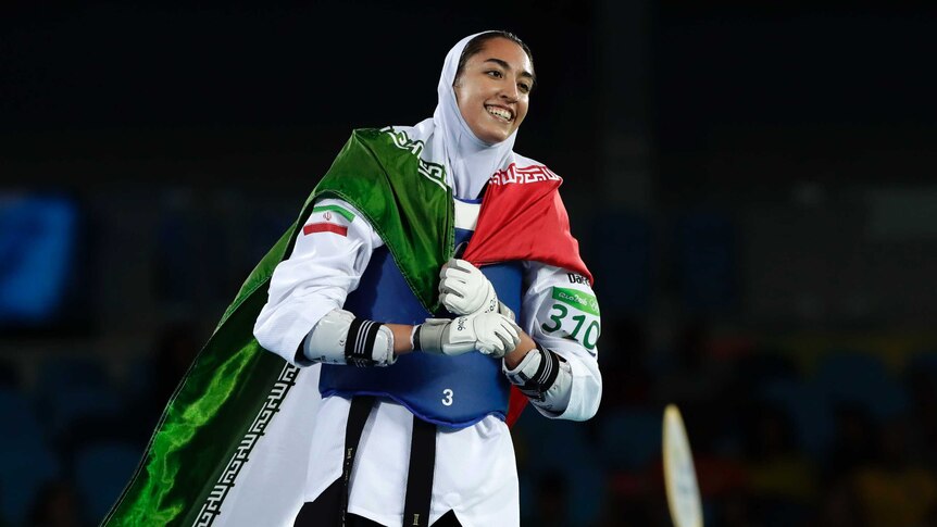 Kimia Alizadeh Zenoorin celebrates with the Iran flag after securing taekwondo bronze.