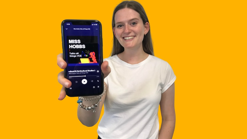 A young woman holds a phone up, showing an educational podcast.