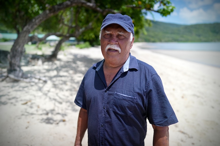 A man smiles with the beach in the background.