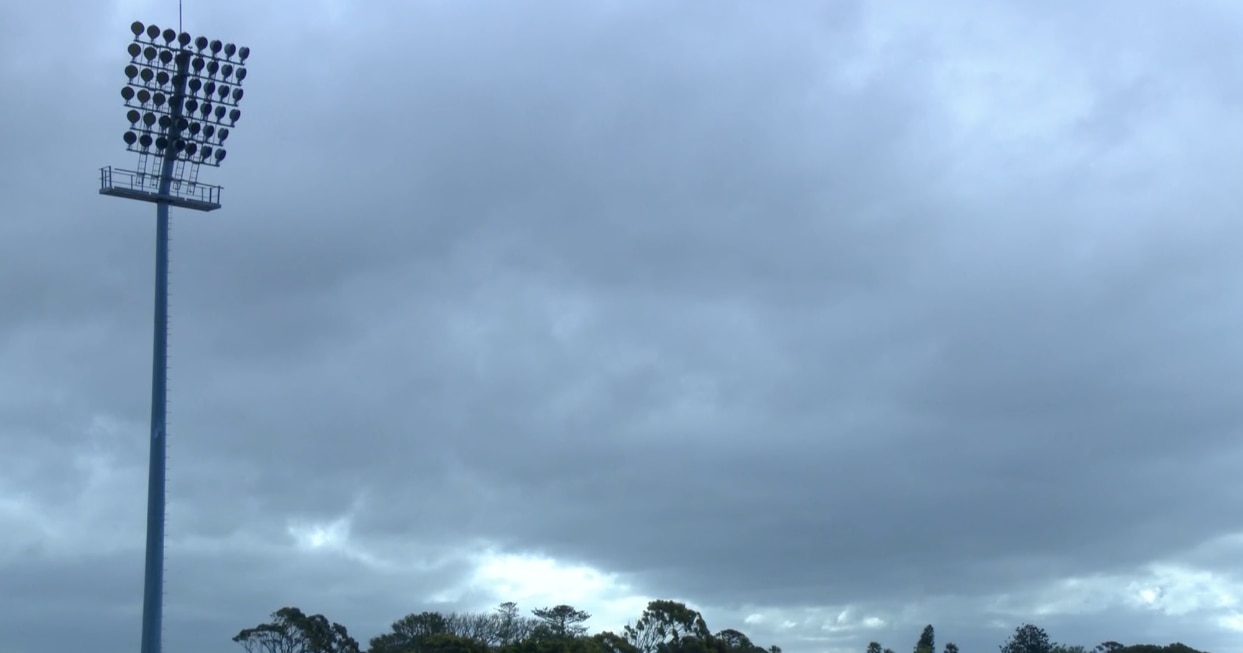 A dark overcast sky with a large floodlith to the left.