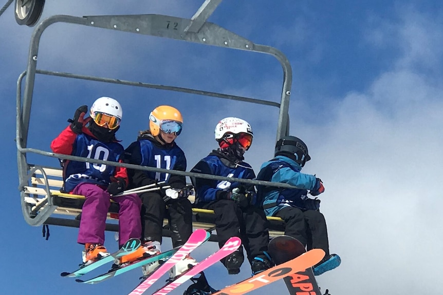 Four skiers sit on a chairlift.