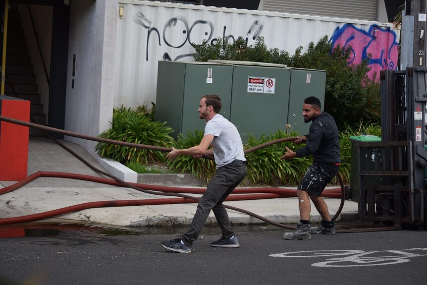 Two men holding a fire hose