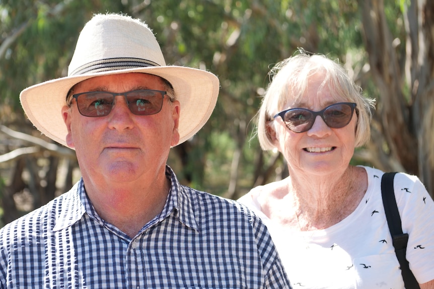 A man with a white hat and sunglasses standing next to a woman with sunglasses