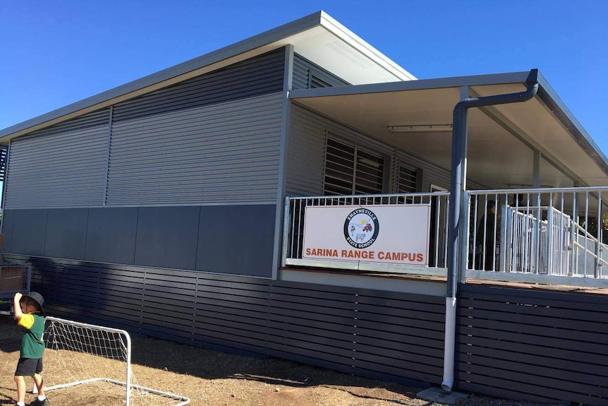 A demountable school building with a sign 'Sarina Range Campus' and a child in front of a soccer goal net