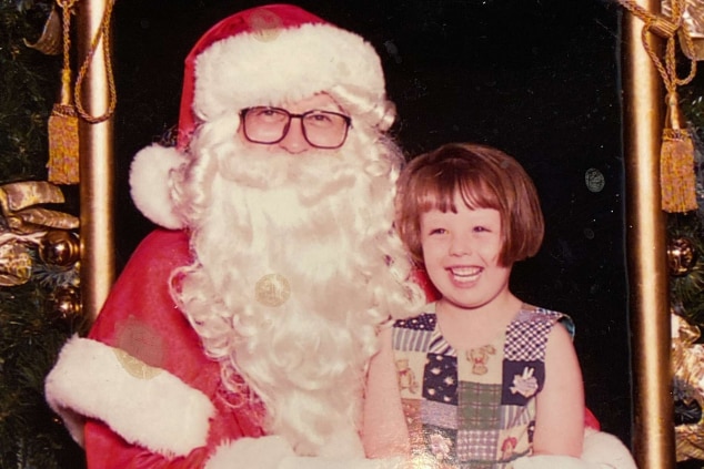 A small girl on Santa's lap smiling.
