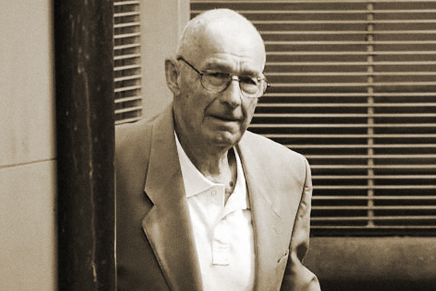 Roger Rogerson, a man wearing glasses, blazer and shirt leaves a building