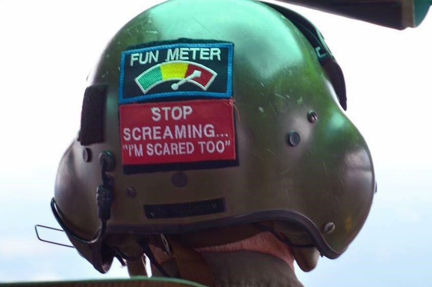 The back of a pilot's helmet with a sticker saying 'stop screaming... I'm scared too'