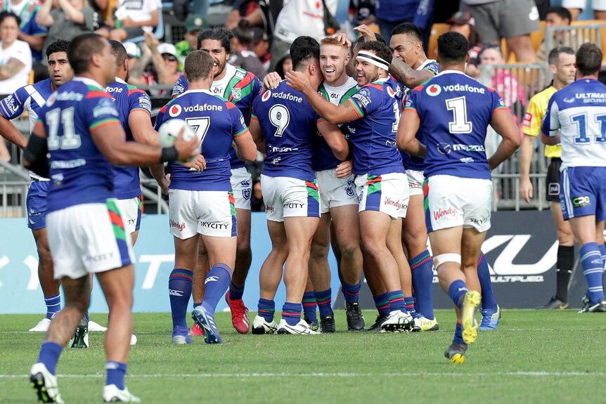 Players crowd around a tryscorer in a rugby league match in Auckland.