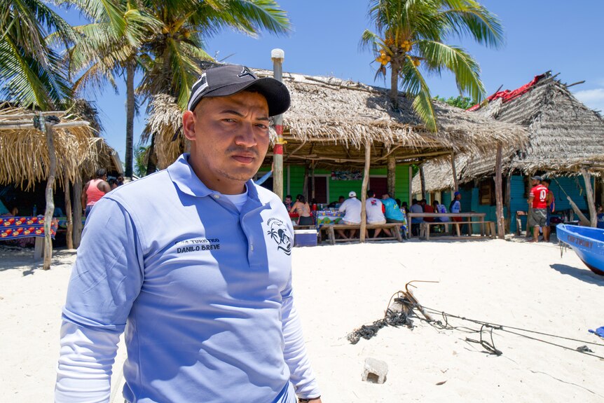 Danilo stands on a beach.