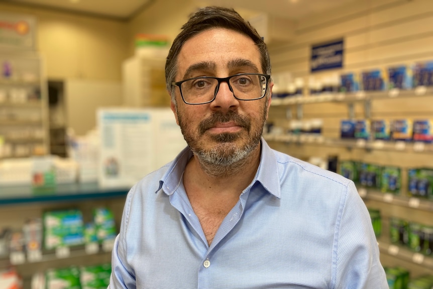 Pharmacist Angelo Bonacci, who has short brown hair and a neat beard, in his pharmacy.