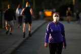 A woman is wearing a face mask and walking outside