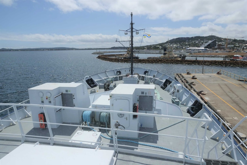 A view out the front windows of a big ship docked in a port.