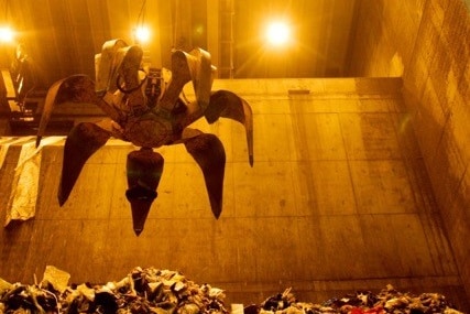 A robotic claws scoops up garbage in an incinerator