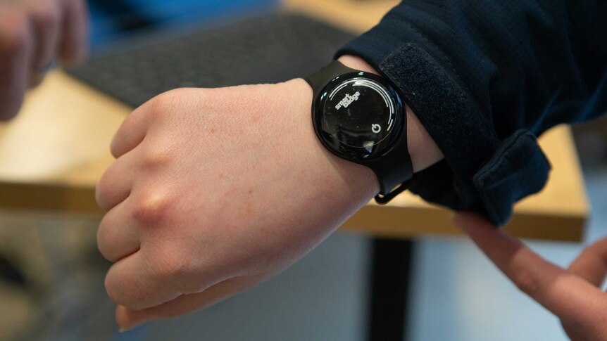 A man's arm with a device attached like a watch.