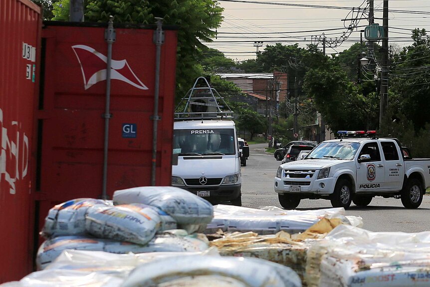 A police vehicle is seen near a container and piles of fertiliser.
