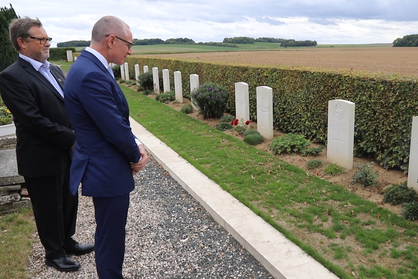Two men in suits pay their respects at war gravesite in France