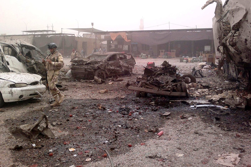 Iraq security personnel inspect the site of a car bomb attack at Jadidat al-Shatt.