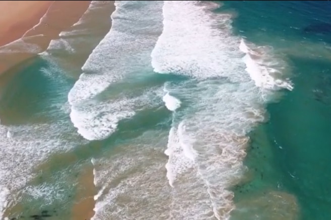 An aerial shot of waves at a surf beach. 