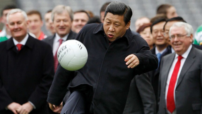 Xi Jinping kicks a football in front of a crowd.