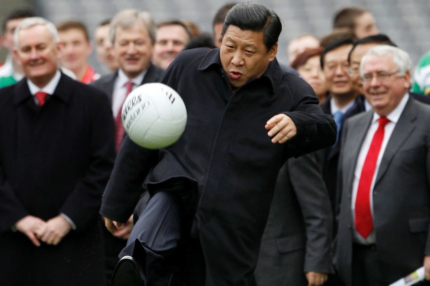 Xi Jinping kicks a football in front of a crowd.