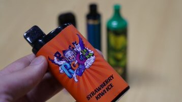 Close-up of vape container with other vapes visible in the background. 