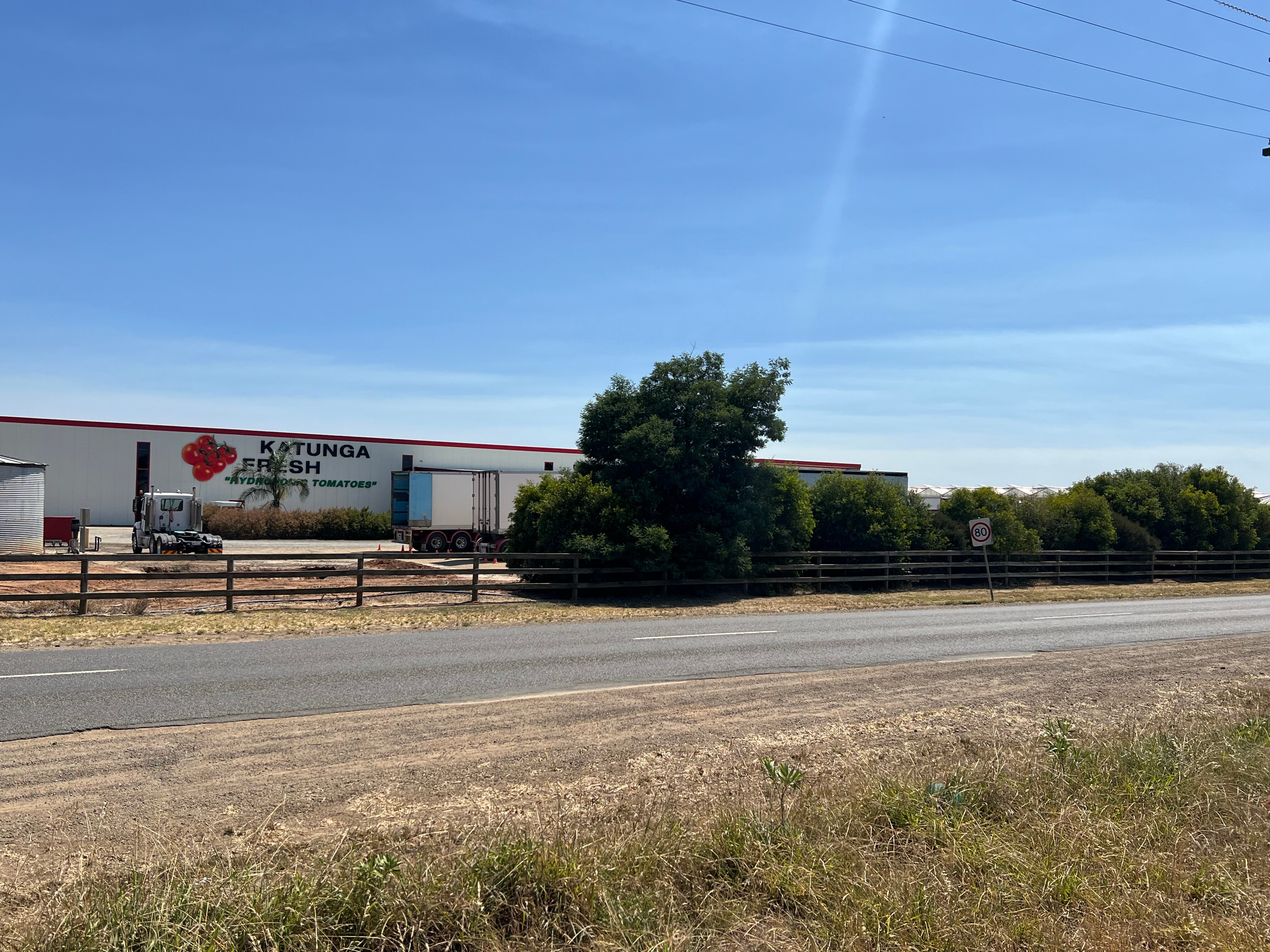 A building with a sign reading Katunga Fresh, with various trucks parked out the front.